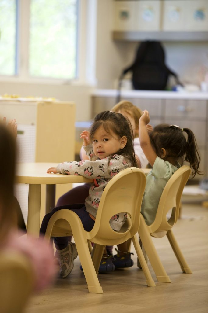 niños pequeños sentados a una mesa en una clase de inglés