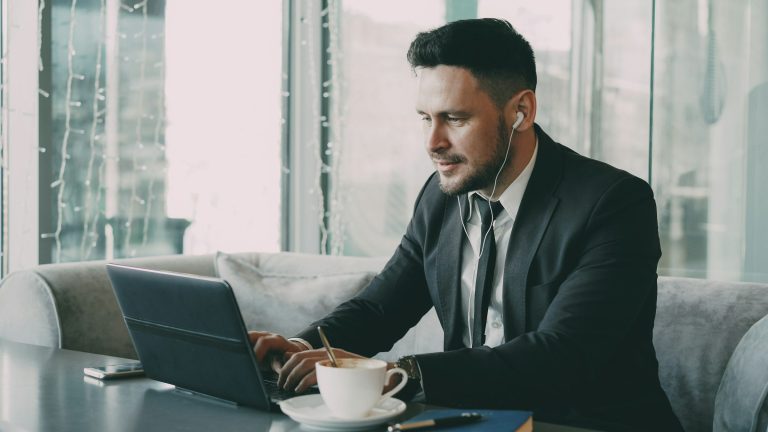 Candidato con traje trabajando con el portátil y auriculares